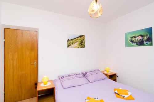 a bedroom with a white bed with purple pillows at Guest House Kola in Slano