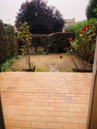 une passerelle en briques dans un jardin avec des roses rouges dans l'établissement CERES, à Gréoux-les-Bains