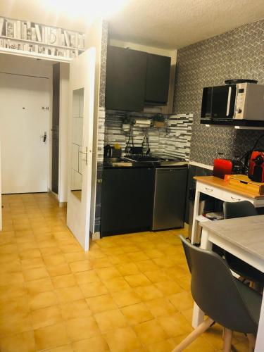 une cuisine avec des armoires noires et un plancher en bois dans l'établissement CERES, à Gréoux-les-Bains