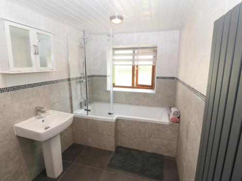 a bathroom with a sink and a tub and a shower at Y Berth Ddu Farmhouse in Caernarfon
