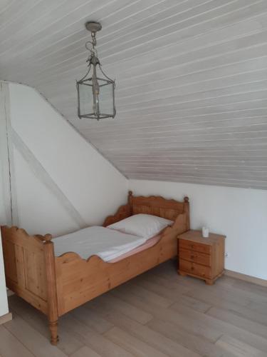 1 dormitorio con cama de madera y lámpara de araña en Kehrmühle en Ober Kostenz