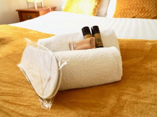 un panier avec deux bouteilles de vin sur un lit dans l'établissement Arkas YourHostHelper, à Périers-sur-le-Dan