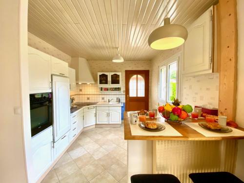 - une cuisine avec des placards blancs et une table avec des fruits dans l'établissement Arkas YourHostHelper, à Périers-sur-le-Dan