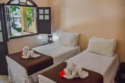 a room with two beds with towel animals on them at Pousada Recanto do Lobo in Porto De Galinhas