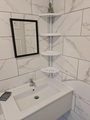 a white bathroom with a sink and a mirror at Large Brick Chalet sleeps 6 mins to beach and amusements in Leysdown-on-Sea