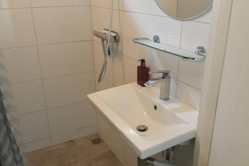 La salle de bains blanche est pourvue d'un lavabo et d'une douche. dans l'établissement Sfeervolle villa in Gasselte Drenthe bij Hemelriek, à Gasselte