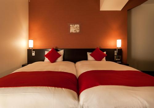 a bedroom with two beds with red and white pillows at Daiwa Roynet Hotel Okayama Ekimae in Okayama
