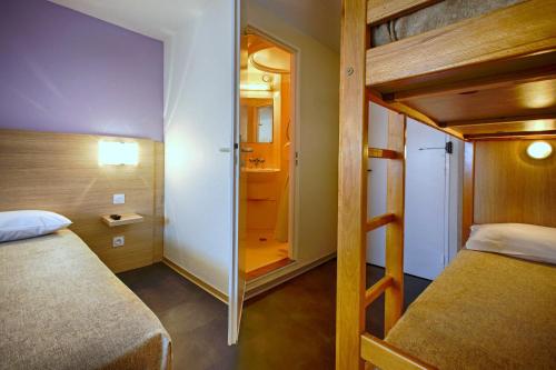 a small bedroom with a bunk bed and a mirror at Hotel Formule Club in Cenon
