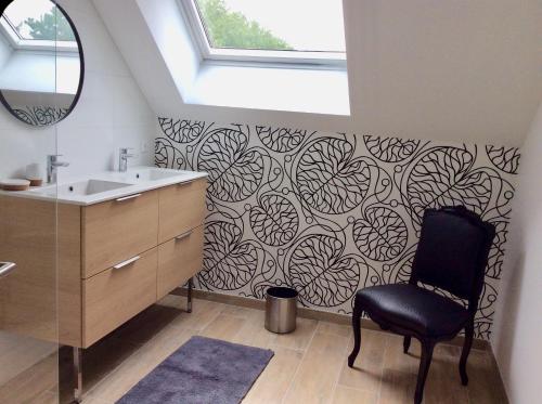 a bathroom with a black chair next to a sink at Aux Bois Dorés de la Ferme de sorval, animaux de la ferme, fitness in Selvigny