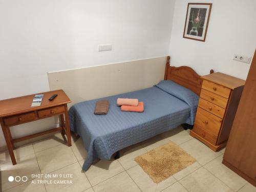 プエルト・デル・ロサリオにあるFuerteventura Puerto del Rosario Cataluñaの青いベッドとデスク付きの小さなベッドルーム1室が備わります。