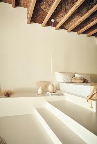 a white bedroom with a bed and wooden ceilings at AF Lindia Nature Design Hotel in Líndos