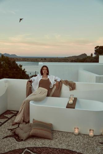 a woman is sitting on a white couch at AF Lindia Nature Design Hotel in Líndos
