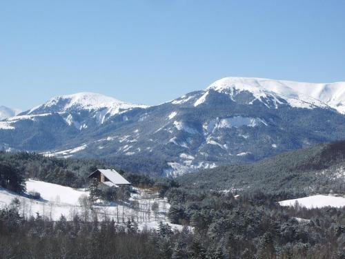 a snow covered mountain range with a house in the foreground at Domaine de l'Adoux in Saint-Jean Montclar