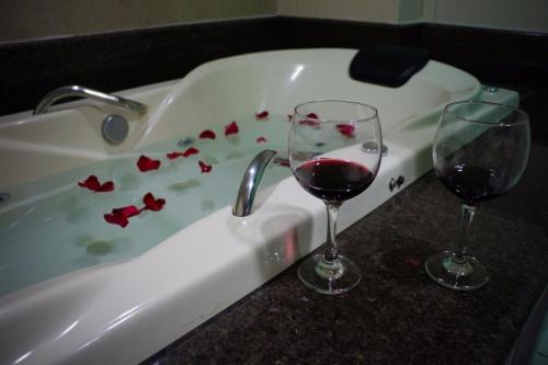 due bicchieri di vino rosso seduti in una vasca da bagno di Hotel Guapindaia Praça a Rio Branco