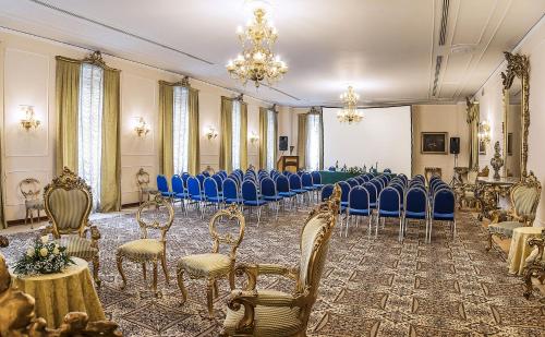 a room filled with blue chairs and a room with a stage at Grand Hotel Telese in Telese