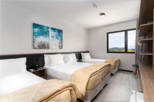 a hotel room with two beds and a window at Flat em Frente ao Parque Beto Carreiro in Penha