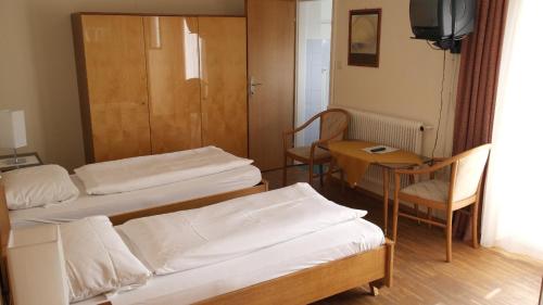 a room with three beds and a table and a chair at Landhaus Waldfrieden in Lassnitzhöhe