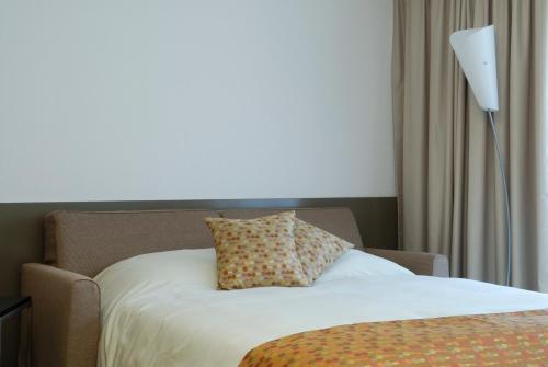 a bed with a pillow on it next to a lamp at Aparthotel Adagio Bordeaux Centre Gambetta in Bordeaux