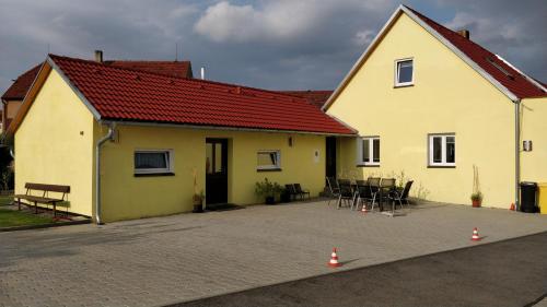 a yellow house with a table and chairs in front of it at Penzion Rozárka in Přísečná