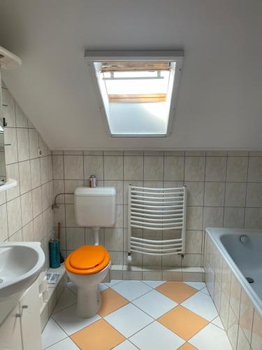 a bathroom with a toilet with an orange lid at Julius Apartman in Hajdúszoboszló
