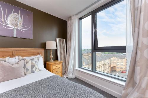 a bedroom with a bed and a large window at SECC Hydro Executive 7 Apartment in Glasgow