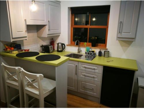 a kitchen with a sink and a counter with two chairs at Bluebell Cottage - with hottub in Newry