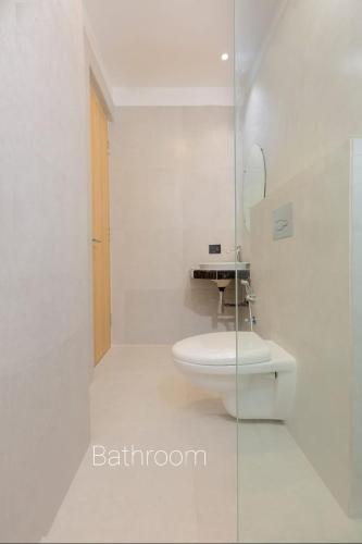a white bathroom with a toilet and a sink at NK7 Hotel in Kolkata