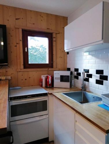 a kitchen with a stove and a sink and a window at Très bel appartement face au lac de Bozel in Bozel