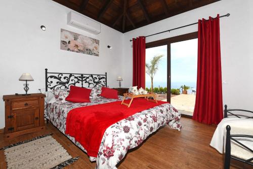 a bedroom with a bed with a red comforter at Casa Pino Arujo in Tijarafe