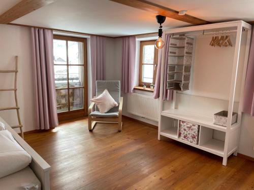 a room with a bed and a chair and windows at Bergien in Halblech