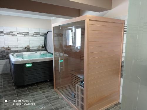uma casa de banho com uma cabina de duche em vidro e um lavatório. em Karos Bianco Apartmanház em Zalakaros