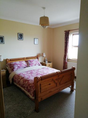 a bedroom with a bed with a wooden frame and a window at Craig Cottage Self-catering in Bushmills