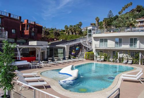 une grande piscine avec des chaises et un bâtiment dans l'établissement Hotel Malavoglia, à Aci Trezza