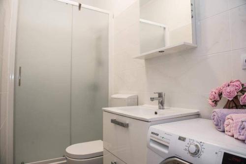 a white bathroom with a sink and a toilet at Apartman Cezar2 in Rogoznica