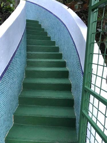 a stairway with a green backdoor to a tennis court at FLOR DE PARAISO BUNGALOWS in Montezuma