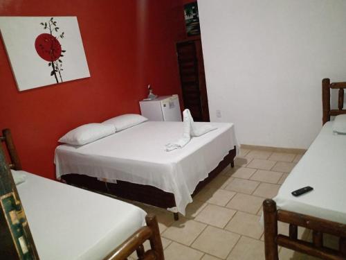 two beds in a room with red walls at Pousada e Restaurante Sol e Lua in Mucuri