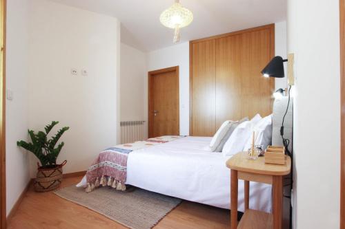 a bedroom with a large white bed and a table at Casa do Condado in Vilarinho