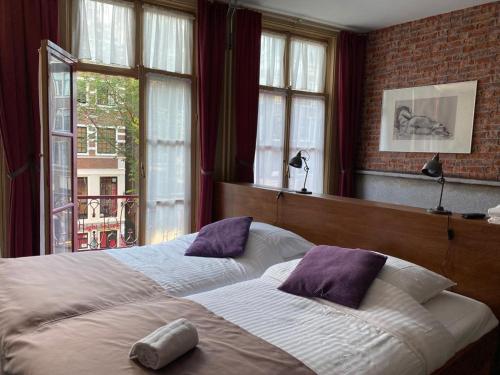 1 dormitorio con 2 camas y ventana en Hotel & bar Royal taste Amsterdam, en Ámsterdam