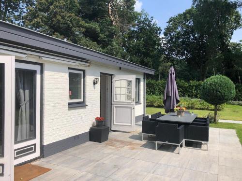 un patio con una mesa y una sombrilla junto a un edificio en Unique chalet in Harderwijk with large garden en Harderwijk