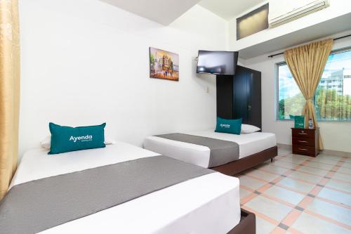 Ayenda Oporto Suites في كوكوتا: غرفة فندقية بسريرين وتلفزيون
