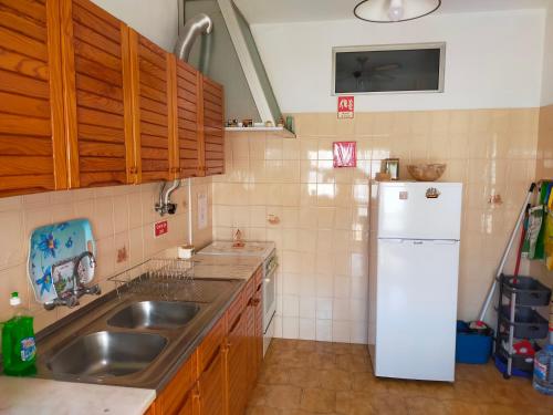 a kitchen with a sink and a white refrigerator at Cantinho do Zé e da Júlia in Lagos