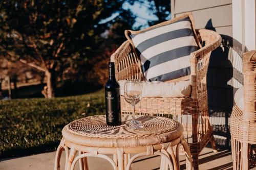 a bottle of wine sitting on a wicker table with a glass at The Red Hill Nest in Glanmire