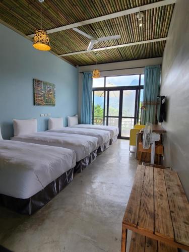 a row of beds in a room with a table at 達芭凱民宿 Tabakai B&B in Xinyi