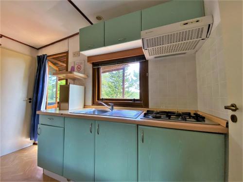 a kitchen with blue cabinets and a sink and a window at Belvilla by OYO Lovely bungalow with a shared pool in San Giusto