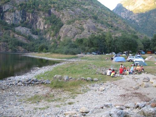 a group of people sitting on the rocks near a lake at Sæbø Camping in Eidfjord