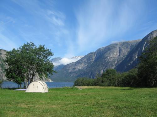 a tent in a field with a lake and mountains at Sæbø Camping in Eidfjord