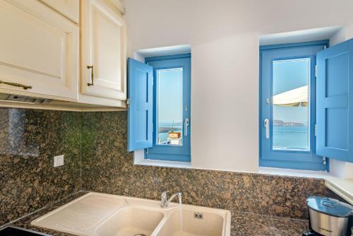 a kitchen with blue windows and a sink at Golden Grey Goose in Fira