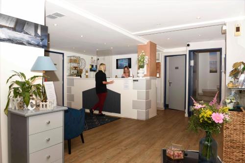 a woman standing at a counter in a hair salon at Azur Hotel in Balaruc-les-Bains