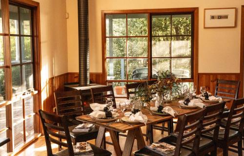 a dining room with a table and chairs and windows at Little Norfolk Bay Events and Chalets in Taranna