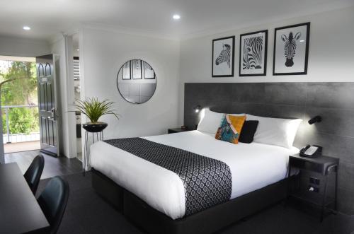 a bedroom with a large white bed and some pictures on the wall at Orana Motel in Dubbo